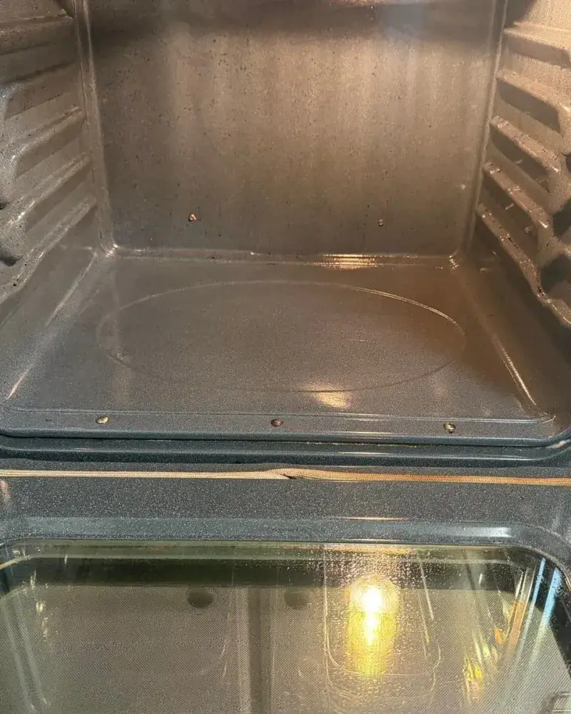 Inside of a clean oven with a shining back wall and racks