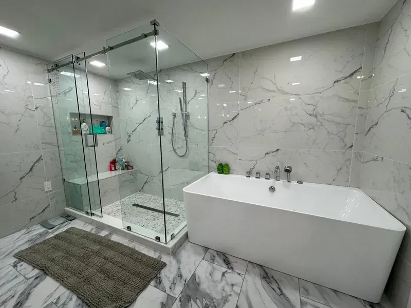 A spotless marble bathroom with a glass shower and freestanding bath